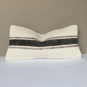 May include: White pillow with black and gray striped pattern. The pillow is made of a woven fabric.