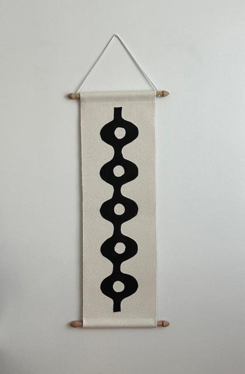 K&ouml;nnte beinhalten: Ein schwarz-wei&szlig;es Wandbehang mit geometrischem Muster. Das Muster besteht aus einer Reihe von verbundenen Ovalen, wobei sich in der Mitte jedes Ovals ein wei&szlig;er Kreis befindet.