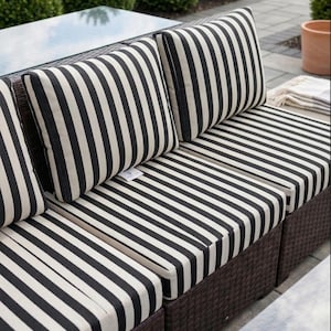 Puede incluir: Sofá seccional para exteriores con cojines y cojines traseros a rayas blancas y negras. El sofá tiene una estructura de mimbre marrón oscuro y una mesa con tapa de cristal. Los cojines y almohadas tienen un diseño clásico y náutico.