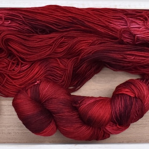 Puede incluir: Un conjunto de hilo de color rojo intenso, que incluye una madeja grande, suelta y sin retorcer, y una madeja m&aacute;s peque&ntilde;a y apretada. El hilo presenta una rica paleta de colores variados que van desde el carmes&iacute; brillante al burdeos.