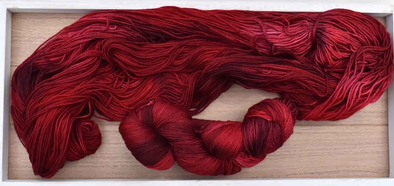Puede incluir: Un conjunto de hilo de color rojo intenso, que incluye una madeja grande, suelta y sin retorcer, y una madeja m&aacute;s peque&ntilde;a y apretada. El hilo presenta una rica paleta de colores variados que van desde el carmes&iacute; brillante al burdeos.
