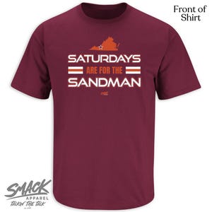 May include: A maroon t-shirt with the text "SATURDAYS ARE FOR THE SANDMAN" in white. Above the text is an orange outline of a state with a star. The shirt also has the "SMACK APPAREL" logo.