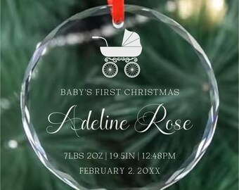 May include: Clear glass Christmas ornament with a red ribbon. The ornament features a white baby carriage graphic and the text "BABY'S FIRST CHRISTMAS" and "Adeline Rose". It also includes the baby's birth details: 7lbs 2oz, 19.5 inches, and the date and time of birth.