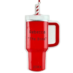 K&ouml;nnte beinhalten: Roter, becherf&ouml;rmiger Christbaumschmuck mit wei&szlig;em Deckel und Griff. Er hat einen rot-wei&szlig; gestreiften Strohhalm und den Text "Rebecca" und "The Boss". Das Jahr "20XX" steht unten.