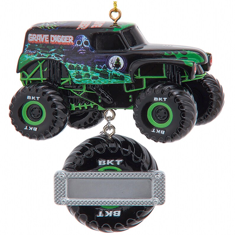 May include: A black and green Grave Digger monster truck ornament with large tires and the text "Grave Digger." The ornament includes a silver tag. The truck has a skull and graveyard design.