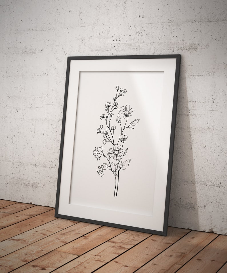 以下が含まれることがあります： 黒いフレームに入った、白黒の線画で描かれた花束のプリント。プリントは、葉と花がついた単一の茎のシンプルなデザインです。