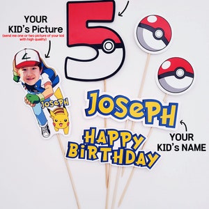 May include: A set of 5 Pokemon-themed cake toppers for a birthday party. The set includes a red and white number 5, a yellow and blue name banner, a red and white Pokeball, a yellow and black Pikachu, and a red and white Pokeball with a blue center. The text on the banner reads "Joseph Happy Birthday".