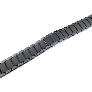 May include: Black metal watch band with a polished finish. The band is made of individual links that are connected together.