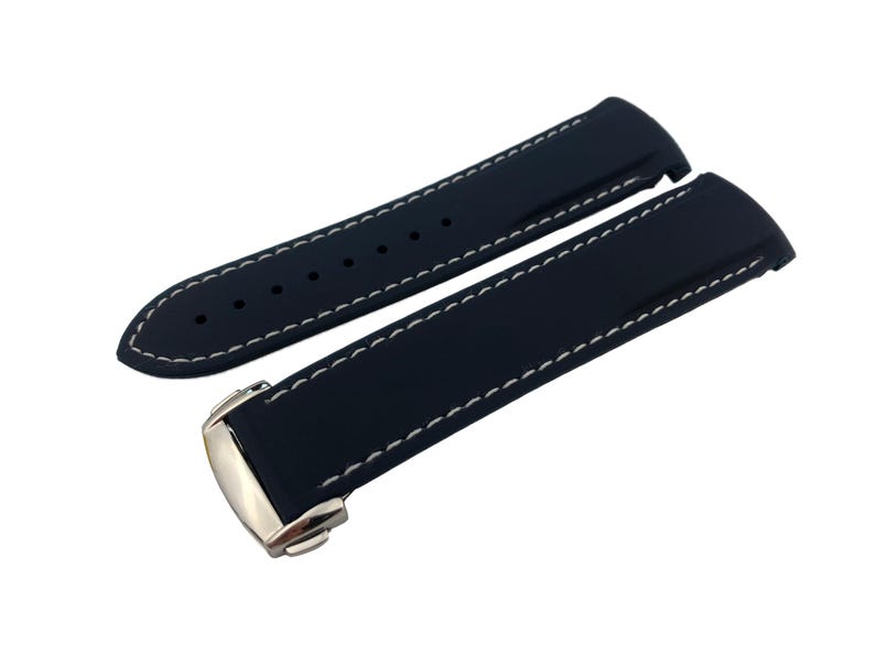 Puede incluir: Una correa de reloj azul marino con costuras blancas. La correa est&aacute; hecha de un material flexible y presenta un cierre plateado. El dise&ntilde;o incluye varios agujeros para el ajuste.