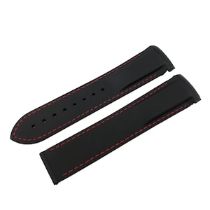 May include: Black watch strap with red stitching. The strap is made of a flexible material and features a classic design. The strap is shown in two pieces, ready for installation on a watch.