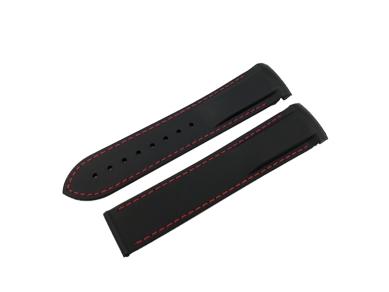 May include: Black watch strap with red stitching. The strap is made of a flexible material and features a classic design. The strap is shown in two pieces, ready for installation on a watch.