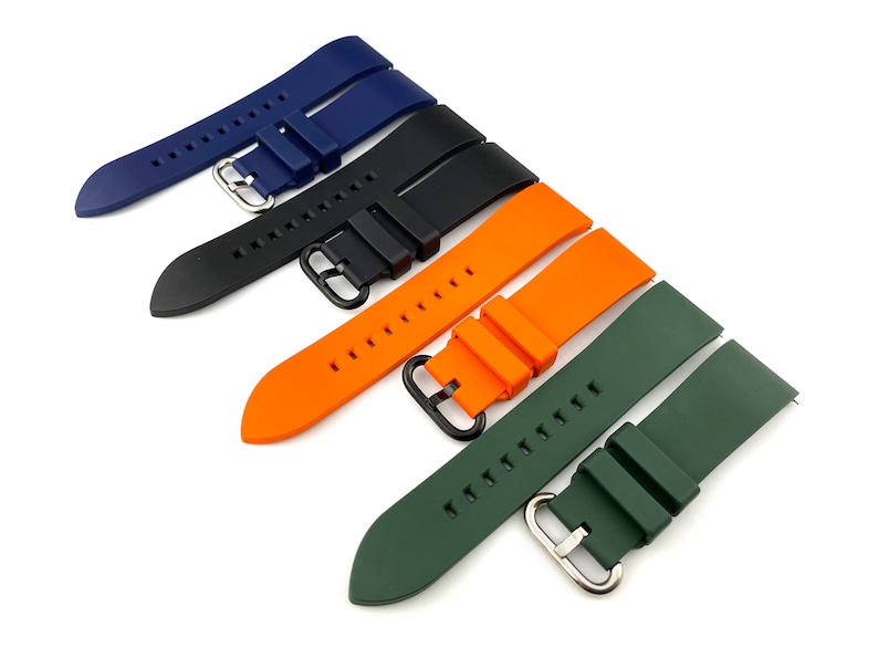 Może przedstawiać: Cztery r&oacute;żne kolorowe paski do zegarka, w tym niebieski, czarny, pomarańczowy i zielony. Paski są wykonane z silikonu i mają zapięcie na klamrę.