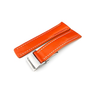 Puede incluir: Correa de reloj de cuero naranja con costuras blancas y hebilla plateada.