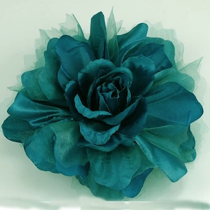 May include: A teal blue fabric rose with a layered tulle design. The rose is a decorative accent for home decor or crafts.
