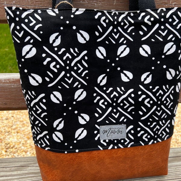 Bold African print tote, accented with cruelty-free vegan leather base. Durable, stylish, and eco-conscious. Your go-to accessory.