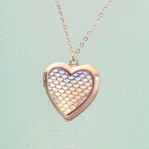 One-of-a-kind gold heart shaped locket with iridescent and pink undertones mermaid/fish scales inlaid on the front! This locket can hold up to 2 photos. It can even be purchased with your photos printed and placed inside by our shop.