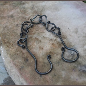May include: A set of two black metal hooks with a decorative design. The hooks are made of twisted metal and have a simple, elegant look.