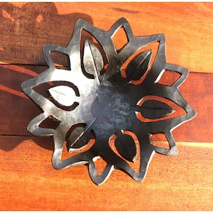 May include: A black metal bowl with a decorative design of leaves. The bowl is made of metal and has a rustic look.