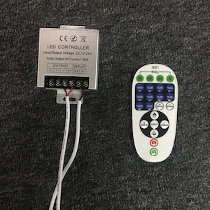 May include: A silver LED controller with a white wire and a white remote control. The controller has the text "LED CONTROLLER" and "Input/Output Voltage: DC12-24V Total Output of Current: 36A". The remote control has buttons for "LED", "Time", "Speed", "Light", "Mode", and percentage increments from 10% to 100%.