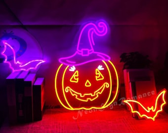 Könnte beinhalten: Ein Neon-Schild in Form eines Kürbisses mit einem Hexenhut. Der Kürbis ist gelb mit einem roten Gesicht und der Hut ist lila. Auf beiden Seiten des Kürbisses befinden sich zwei Neon-Fledermaus-Schilder.