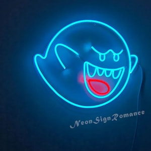 May include: A blue neon sign shaped like a ghost with a red mouth and eyes. The sign says "Neon Sign Romance" at the bottom.