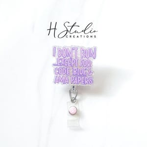 May include: A clear, rectangular badge reel with a purple glitter design that reads "I DON'T RUN EXCEPT FOR CODE BLUE & AMA PAPERS." The badge reel has a silver clip and a clear plastic snap.