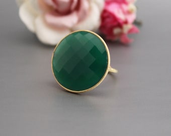 Pode incluir: Um anel de pedra preciosa verde com uma configuração de ouro. O anel apresenta uma grande pedra preciosa redonda e facetada.