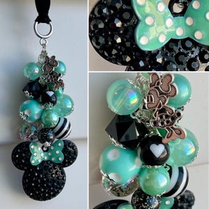 May include: A black and green charm with a Minnie Mouse head design, featuring a green bow with white polka dots. The charm is adorned with various beads, including iridescent, black, white, and striped beads.