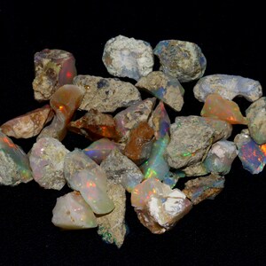 May include: A collection of rough opal stones in various shades of brown, white, and grey with iridescent flashes of color. The stones are irregular in shape and size.
