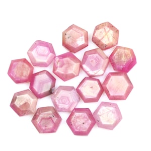 May include: A collection of pink, faceted, hexagonal gemstones. The gemstones are arranged in a loose cluster on a white background.