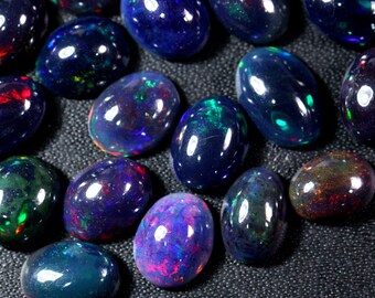 Puede incluir: Una colección de ópalos negros ovalados con colores iridiscentes, incluyendo verde, azul, rojo y morado.