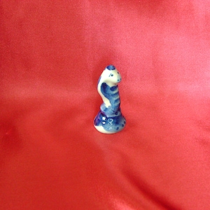 Puede incluir: Una peque&ntilde;a figurita de cer&aacute;mica de una serpiente azul y blanca con la cabeza levantada, de pie sobre una base. La figurita est&aacute; pintada en un estilo tradicional.