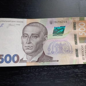 Op de afbeelding: Een Oekraïense 500 Hryvnia-biljet met een portret van Hryhoriy Skovoroda. De biljet heeft een portret van een man op de voorkant, met het nummer 500 in blauw. De Oekraïense tekst is zichtbaar.