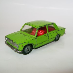 Puede incluir: Un coche de juguete verde con asientos rojos. El coche tiene un aspecto desgastado, vintage.