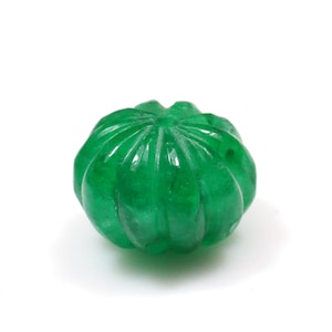 May include: A green carved gemstone bead with a rounded, faceted design.