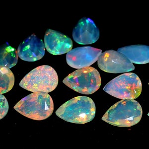 May include: A collection of pear-shaped opals with a faceted cut, displaying a range of colors including blue, green, orange, and yellow. The opals are set against a black background, highlighting their iridescent qualities.