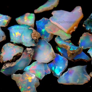 Puede incluir: Una colecci&oacute;n de piedras preciosas de &oacute;palo en bruto en varios tonos de azul, verde y blanco con destellos iridiscentes. Los &oacute;palos son en bruto y tienen un aspecto natural y terroso.