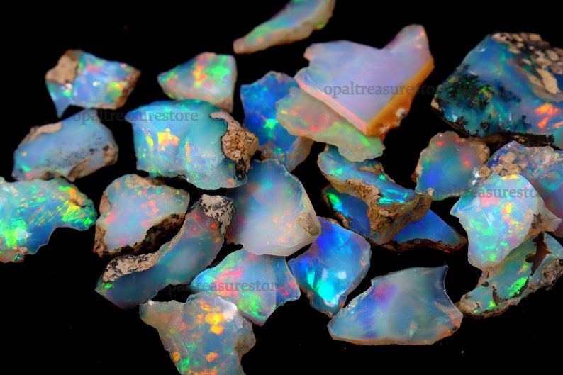 Puede incluir: Una colecci&oacute;n de piedras preciosas de &oacute;palo en bruto en varios tonos de azul, verde y blanco con destellos iridiscentes. Los &oacute;palos son en bruto y tienen un aspecto natural y terroso.