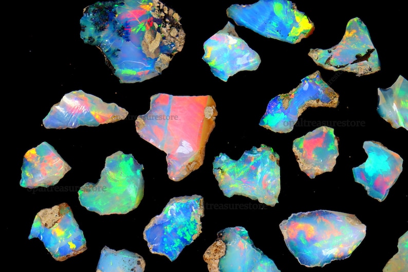 Puede incluir: Una colecci&oacute;n de 15 piedras preciosas de &oacute;palo iridiscente en varias formas y tama&ntilde;os. Los &oacute;palos son una mezcla de azul, verde, rosa y blanco.