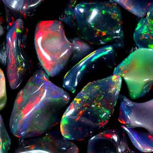 Puede incluir: Primer plano de un grupo de ópalos negros con colores iridiscentes, incluyendo verde, rojo y azul.