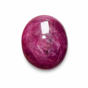 Op de afbeelding: Een gepolijste, ovaalvormige robijn met een diepe magenta en donkerroze kleur. Het oppervlak vertoont natuurlijke insluitingen, een gladde textuur en een reflecterende glans die de gevarieerde, rijke en verzadigde rode tinten benadrukt.