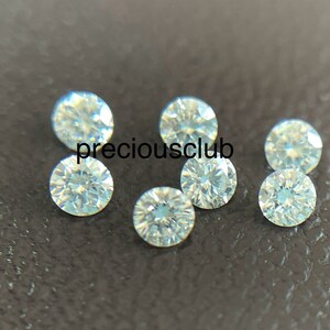 Pode incluir: Sete pedras preciosas redondas, transparentes e facetadas sobre uma superf&iacute;cie marrom escura. As pedras preciosas provavelmente s&atilde;o diamantes.