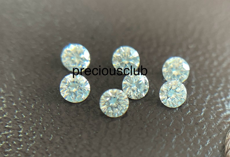 Pode incluir: Sete pedras preciosas redondas, transparentes e facetadas sobre uma superf&iacute;cie marrom escura. As pedras preciosas provavelmente s&atilde;o diamantes.