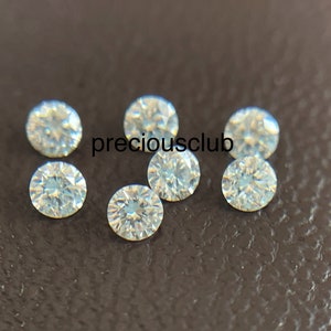 Pode incluir: Sete pedras preciosas redondas, transparentes e facetadas sobre uma superf&iacute;cie marrom texturizada. preciousclub est&aacute; escrito em branco na superf&iacute;cie.