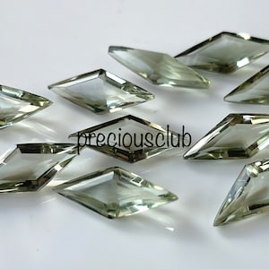 Puede incluir: Diez piedras preciosas verdes facetadas en forma de cometa. Las piedras preciosas son translúcidas y tienen un color verde claro.
