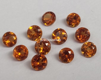 May include: A group of 12 round, faceted, orange gemstones. The gemstones are approximately 5mm in diameter and have a warm, amber-like hue.