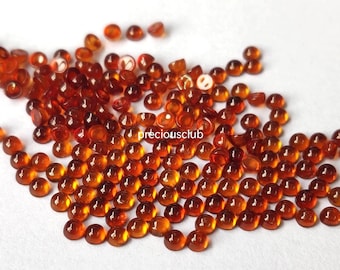 May include: A collection of small, round, translucent orange-brown cabochons with a smooth, domed surface. The stones are scattered across the frame, and the text "preciousclub" is printed in white in the center of the cluster of gemstones.
