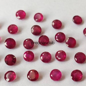May include: A collection of twenty-five round, faceted, deep pinkish-red gemstones arranged in a loose grid pattern. Each stone features a brilliant cut with multiple reflective surfaces. The text "preciousclub" is printed in black in the center.
