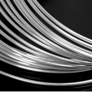 May include: A close-up of a coil of silver wire. The wire is shiny and smooth, and it is coiled tightly together.