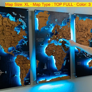 a person pointing at a three-panel world map that is illuminated with blue light, creating a visually striking and unique display.